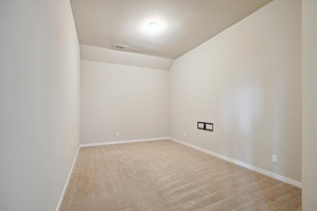 spare room featuring baseboards, carpet, vaulted ceiling, and visible vents