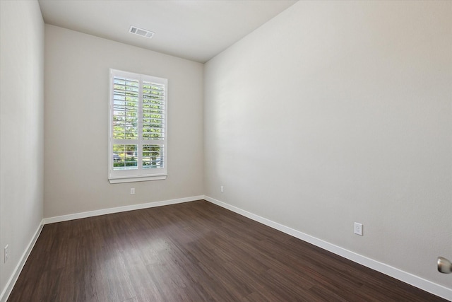 unfurnished room featuring baseboards, dark wood-style floors, and visible vents
