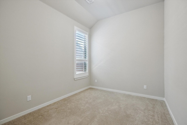 empty room featuring light colored carpet, baseboards, and vaulted ceiling