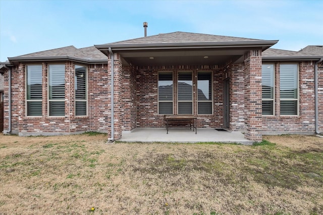 back of house with a patio, a shingled roof, a yard, and brick siding