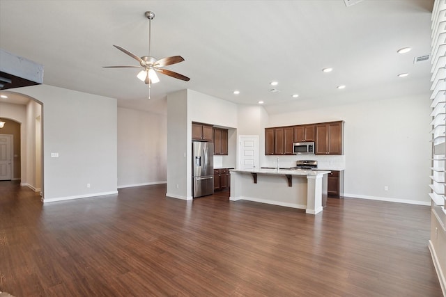 kitchen with ceiling fan, arched walkways, light countertops, open floor plan, and stainless steel appliances