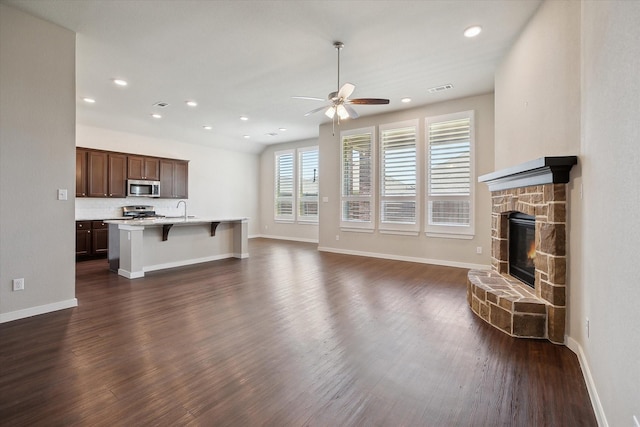 unfurnished living room with ceiling fan, visible vents, a sink, and dark wood-type flooring