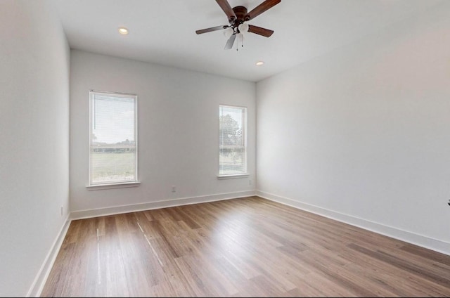 empty room featuring ceiling fan, a healthy amount of sunlight, and light wood-type flooring