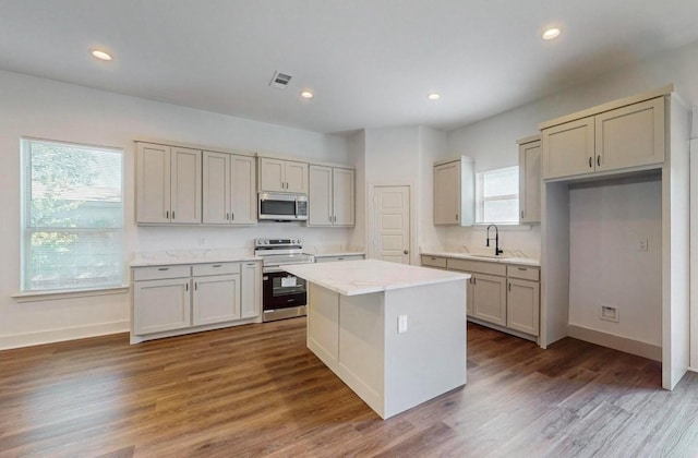 kitchen with sink, dark wood-type flooring, stainless steel appliances, and a center island