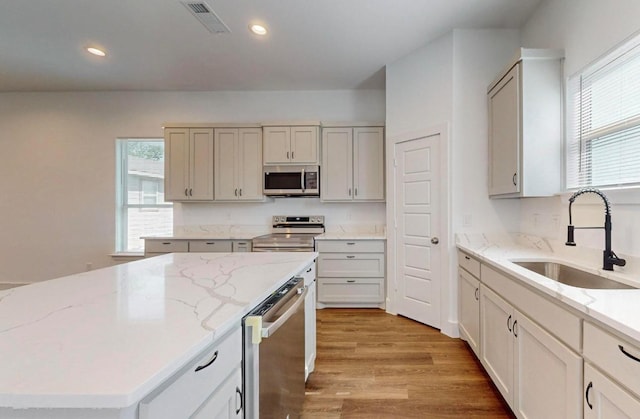 kitchen featuring sink, stainless steel appliances, light hardwood / wood-style floors, and a kitchen island