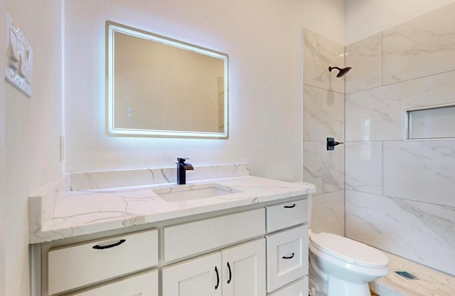 bathroom featuring vanity, tiled shower, and toilet