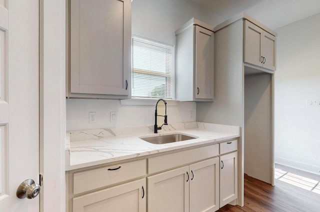 kitchen featuring hardwood / wood-style flooring, light stone countertops, and sink