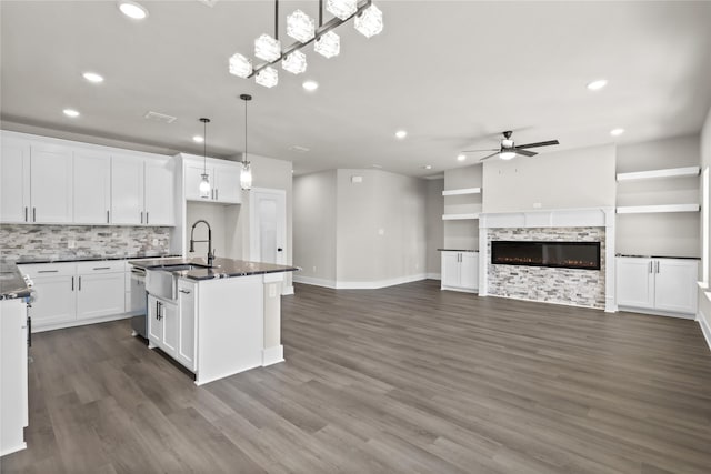 kitchen featuring decorative light fixtures, an island with sink, sink, white cabinets, and ceiling fan