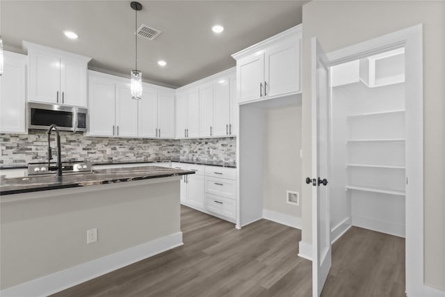 kitchen with white cabinetry, dark wood-type flooring, decorative backsplash, and decorative light fixtures