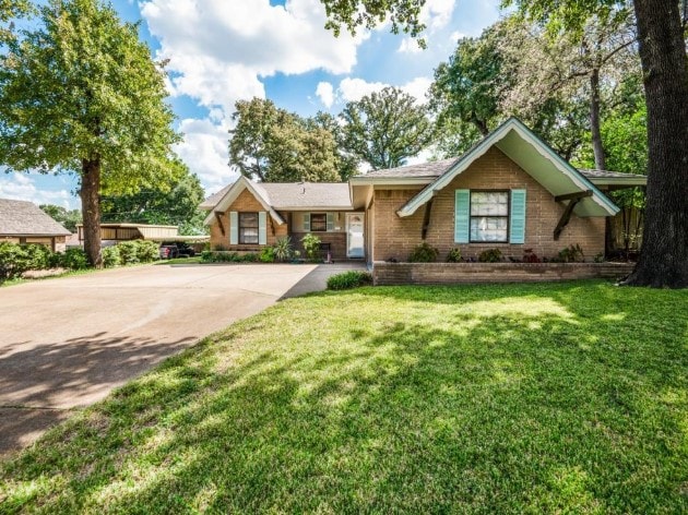 view of front of house featuring driveway, brick siding, and a front yard