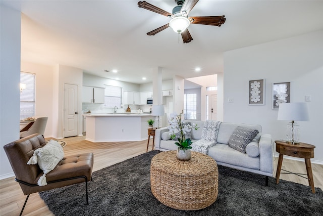 living room featuring sink, light hardwood / wood-style floors, and ceiling fan