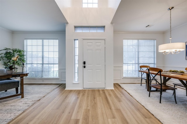 foyer with crown molding and light hardwood / wood-style floors