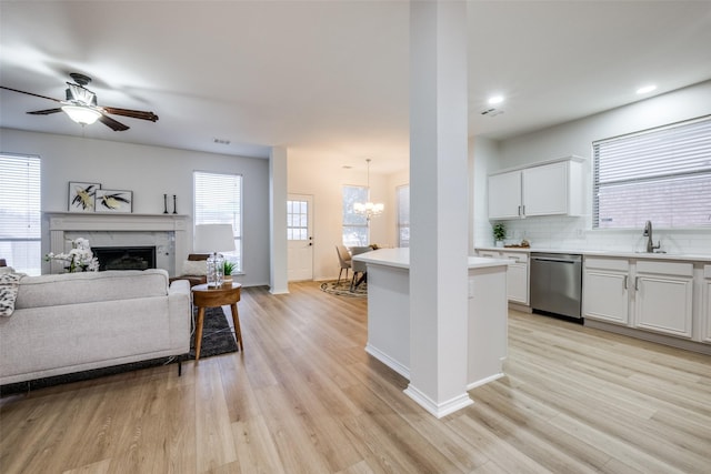 kitchen with white cabinetry, sink, decorative light fixtures, and stainless steel dishwasher