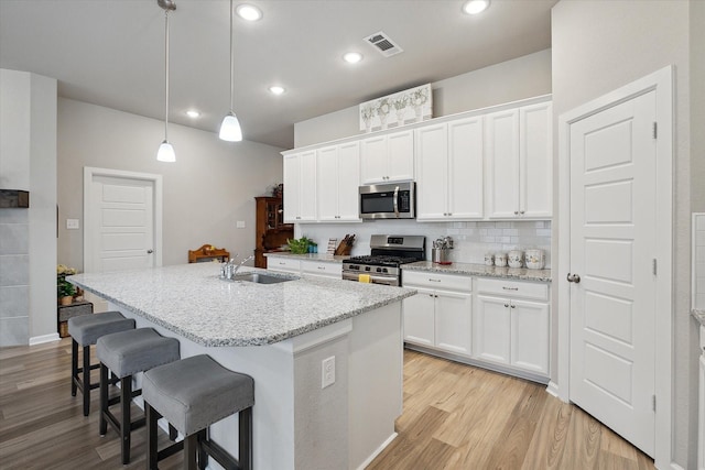 kitchen featuring appliances with stainless steel finishes, white cabinets, and decorative light fixtures