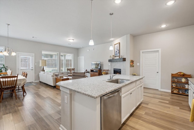 kitchen with light wood-type flooring, open floor plan, a sink, and stainless steel dishwasher