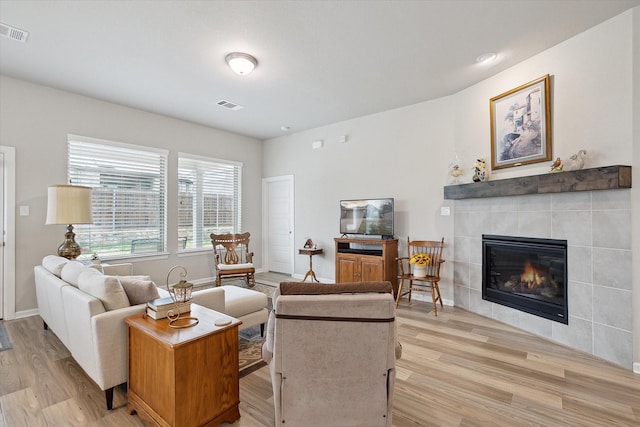 living area with light wood-style flooring, a fireplace, and visible vents