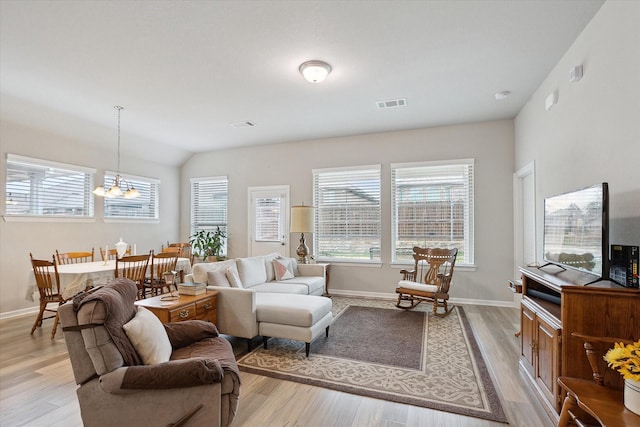 living room with vaulted ceiling, light wood-style flooring, visible vents, and baseboards