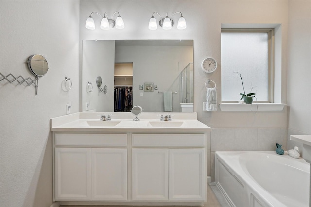 bathroom featuring a garden tub, a spacious closet, a sink, and a shower stall