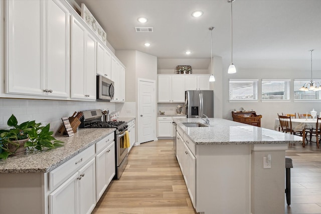 kitchen featuring sink, decorative light fixtures, stainless steel appliances, light hardwood / wood-style floors, and white cabinets