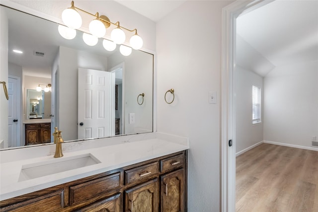 bathroom with visible vents, vanity, baseboards, and wood finished floors