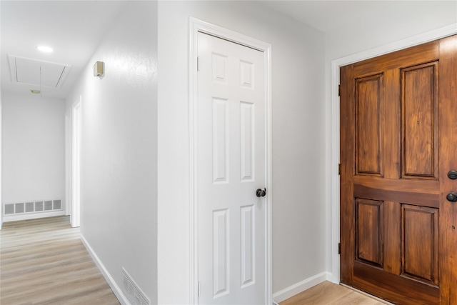 hallway featuring attic access, visible vents, and baseboards