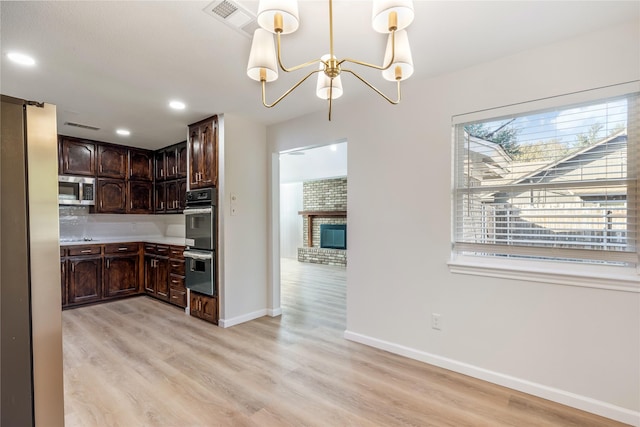 kitchen with appliances with stainless steel finishes, dark brown cabinetry, light wood-style flooring, and tasteful backsplash