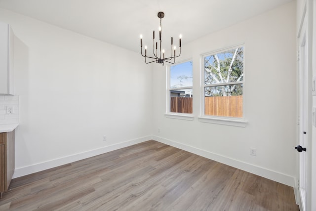 unfurnished dining area featuring an inviting chandelier and light hardwood / wood-style floors