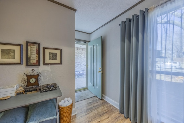 interior space featuring ornamental molding, a textured ceiling, and light wood-type flooring