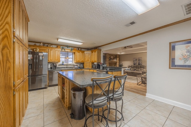 kitchen featuring a kitchen island, sink, a kitchen bar, light tile patterned floors, and stainless steel appliances