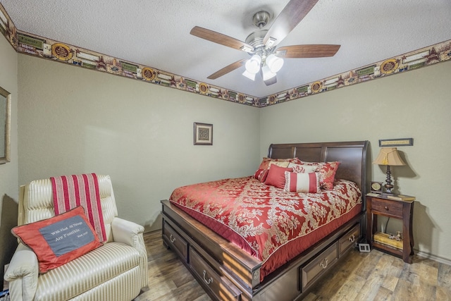 bedroom with ceiling fan, wood-type flooring, and a textured ceiling