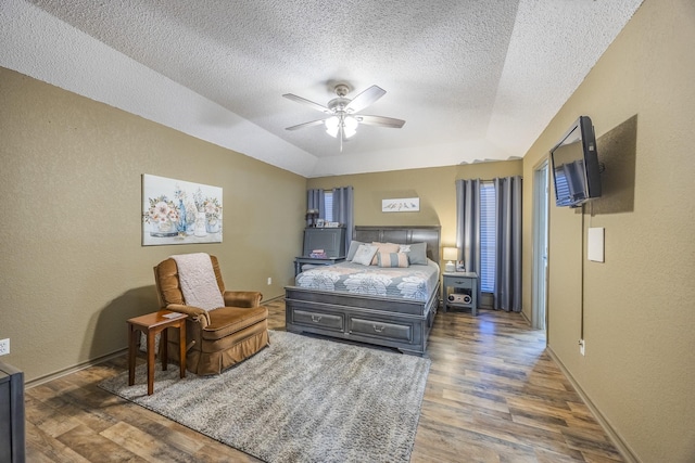 bedroom featuring ceiling fan, dark hardwood / wood-style floors, a raised ceiling, and a textured ceiling