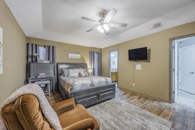 bedroom featuring dark hardwood / wood-style flooring, connected bathroom, a textured ceiling, and ceiling fan