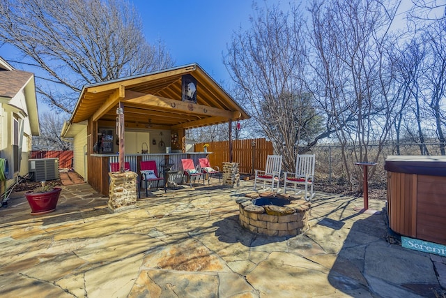 view of patio with central AC unit, a hot tub, an outdoor bar, and an outdoor fire pit