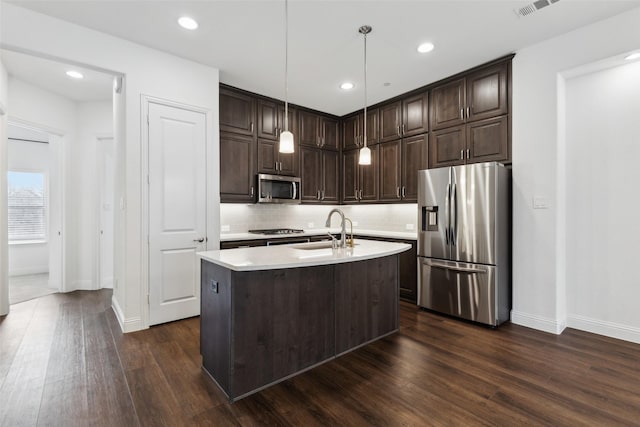 kitchen with sink, a center island with sink, pendant lighting, stainless steel appliances, and decorative backsplash