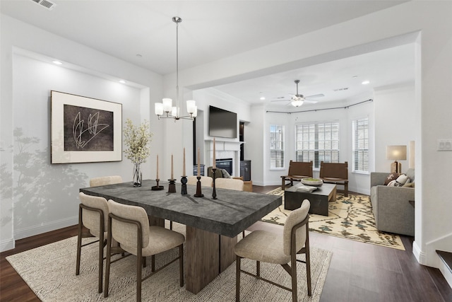 dining space featuring dark hardwood / wood-style floors and ceiling fan with notable chandelier