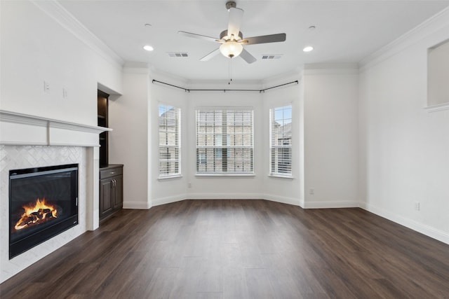 unfurnished living room with a tiled fireplace, dark wood-type flooring, ornamental molding, and ceiling fan