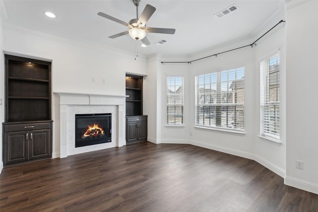 unfurnished living room with crown molding, dark hardwood / wood-style floors, ceiling fan, and built in shelves