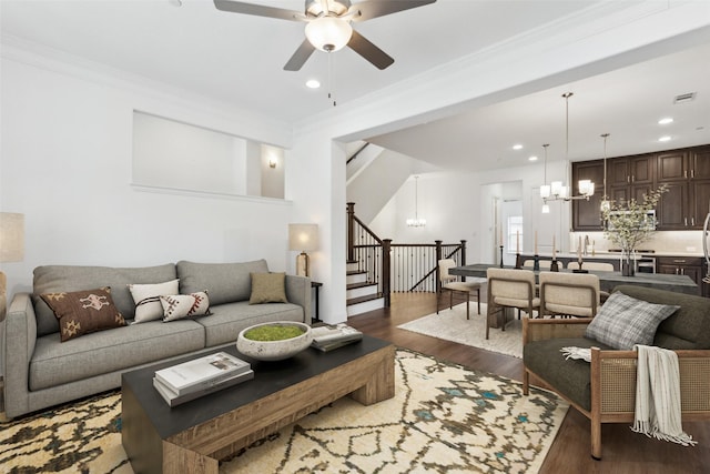 living room with crown molding, dark hardwood / wood-style flooring, and ceiling fan with notable chandelier