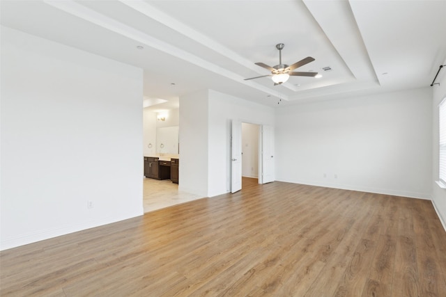 unfurnished room featuring ceiling fan, a raised ceiling, and light hardwood / wood-style floors