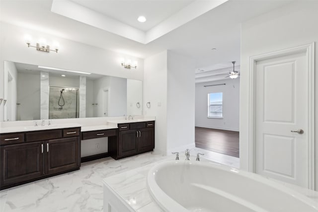 bathroom featuring a raised ceiling, vanity, separate shower and tub, and ceiling fan