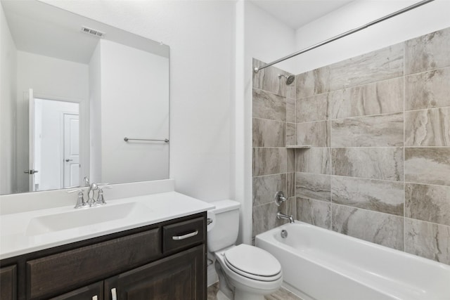 full bathroom with tiled shower / bath, vanity, and toilet