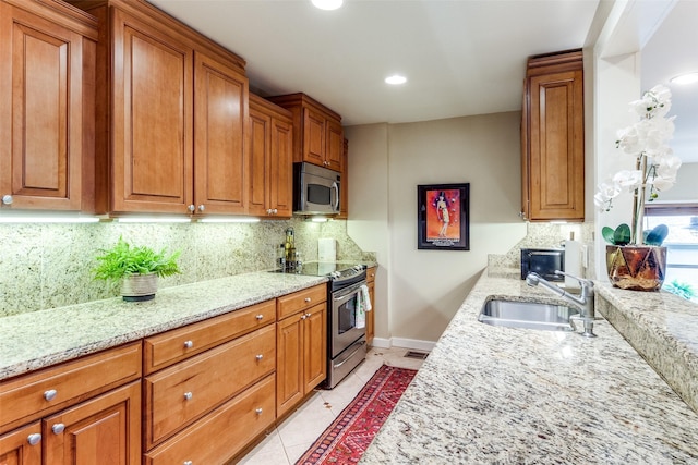 kitchen with light stone counters, sink, light tile patterned floors, and stainless steel appliances