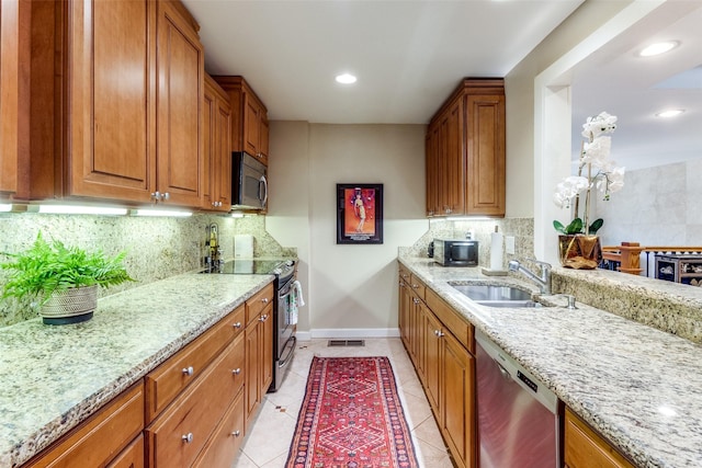 kitchen featuring sink, light stone counters, light tile patterned floors, appliances with stainless steel finishes, and backsplash