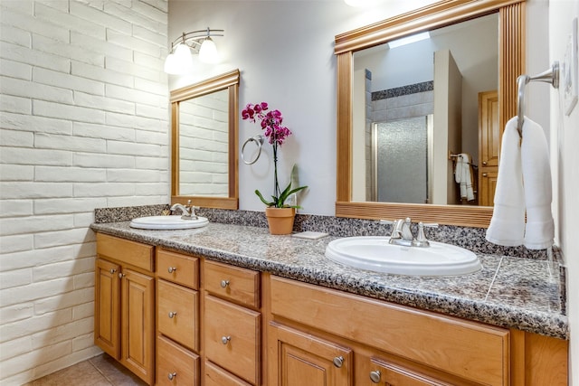 bathroom featuring vanity, brick wall, tile patterned floors, and a shower with shower door