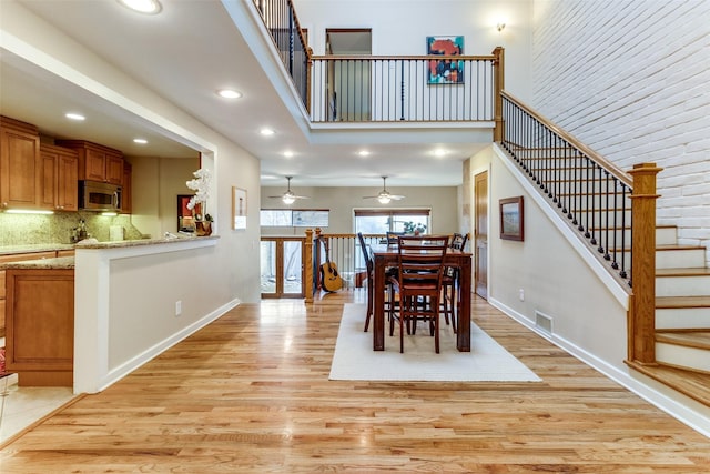 dining space featuring a towering ceiling and light wood-type flooring