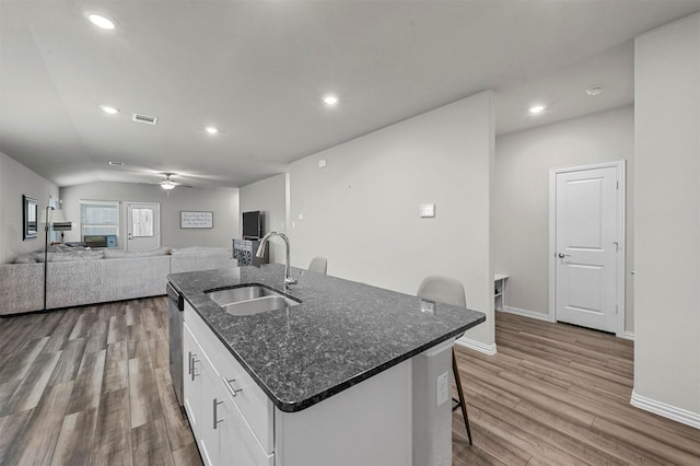 kitchen featuring sink, white cabinetry, a kitchen breakfast bar, a kitchen island with sink, and light hardwood / wood-style floors