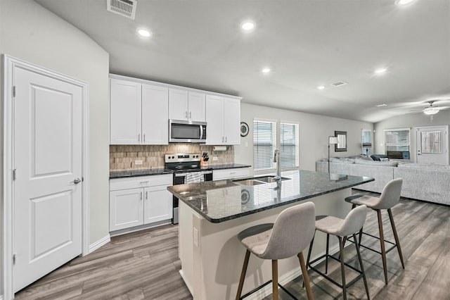 kitchen with appliances with stainless steel finishes, a kitchen breakfast bar, an island with sink, and white cabinets