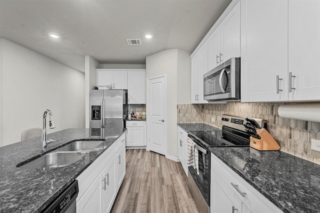 kitchen featuring stainless steel appliances, white cabinetry, sink, and dark stone counters