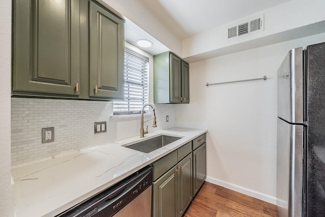 kitchen featuring sink, tasteful backsplash, light hardwood / wood-style flooring, appliances with stainless steel finishes, and light stone countertops