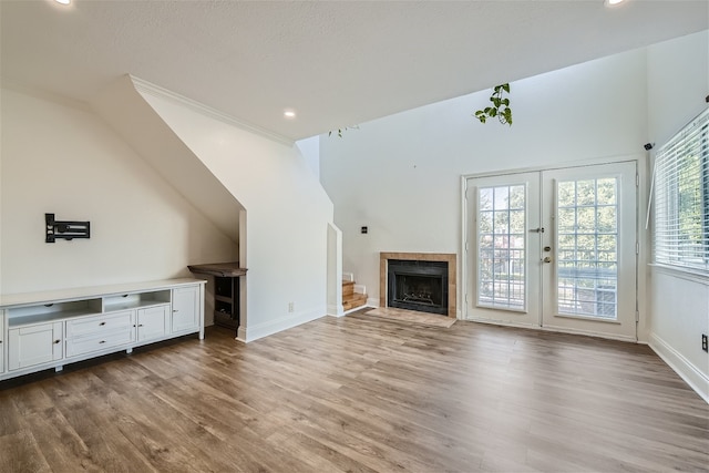 unfurnished living room with a wealth of natural light, light hardwood / wood-style floors, french doors, and a tile fireplace